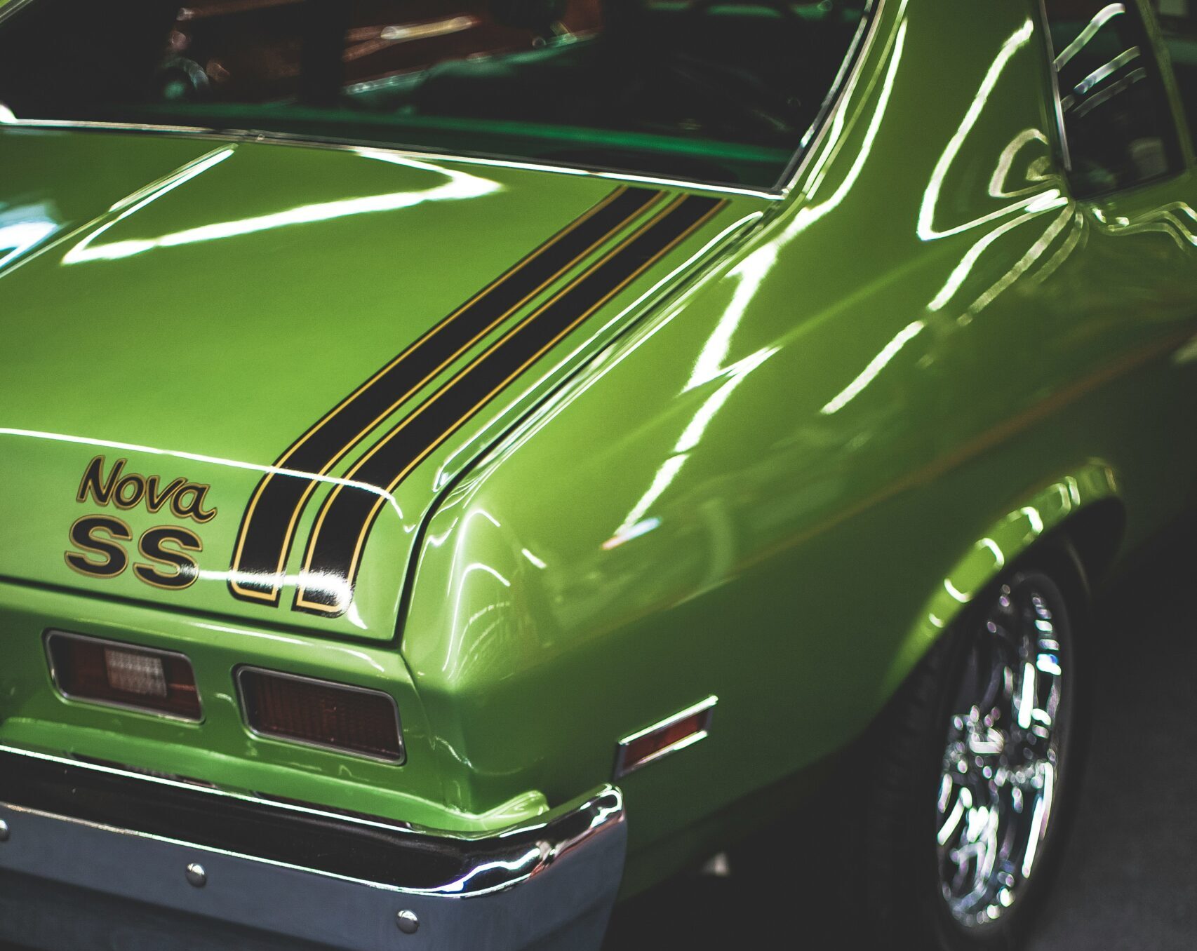 Close-up of the rear end of a vibrant green vintage car with 'Nova SS' branding, showcasing the glossy, durable finish.