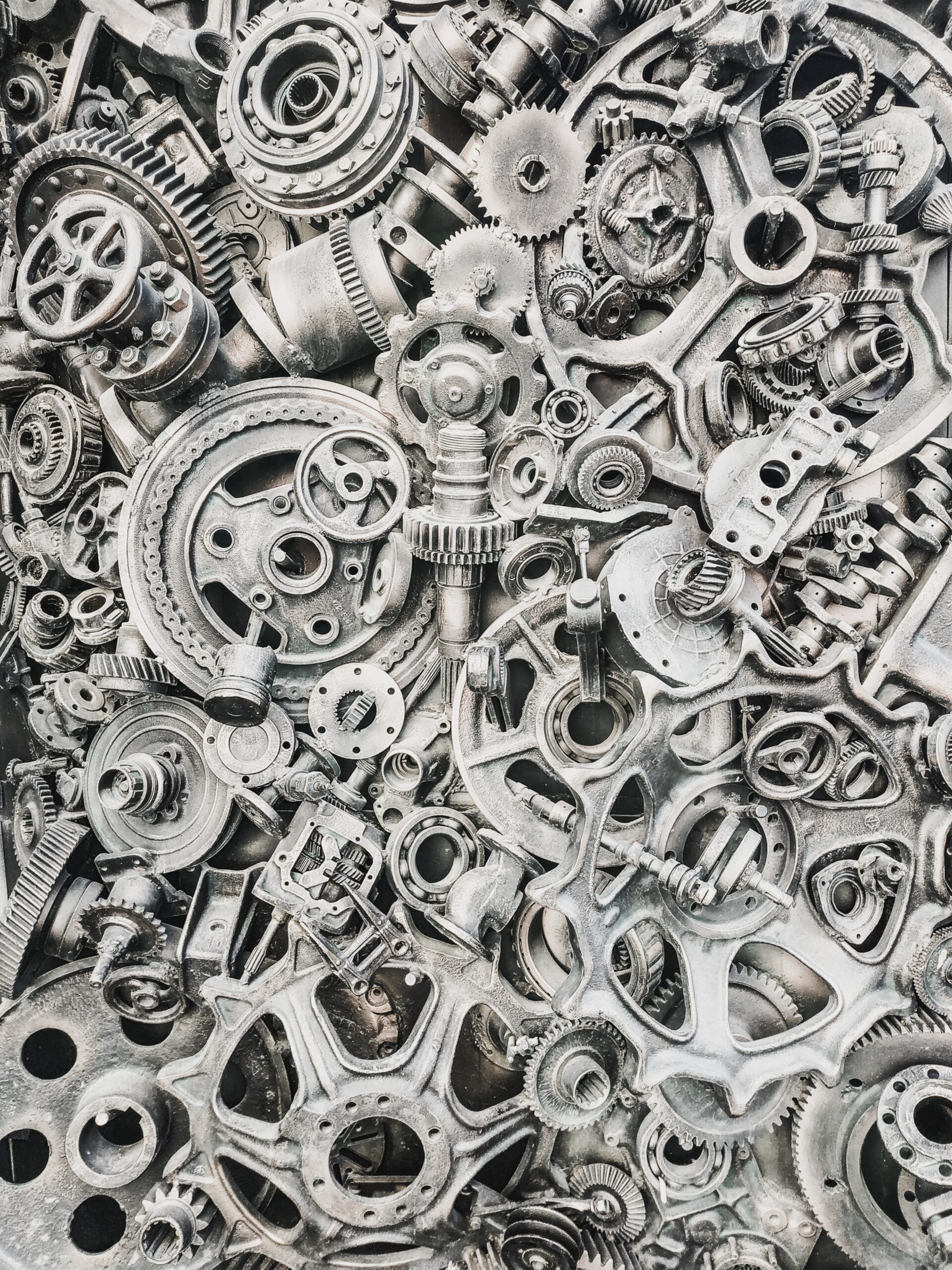 Close-up of various mechanical gears and metal components, representing the industrial applications of Hafnium compounds