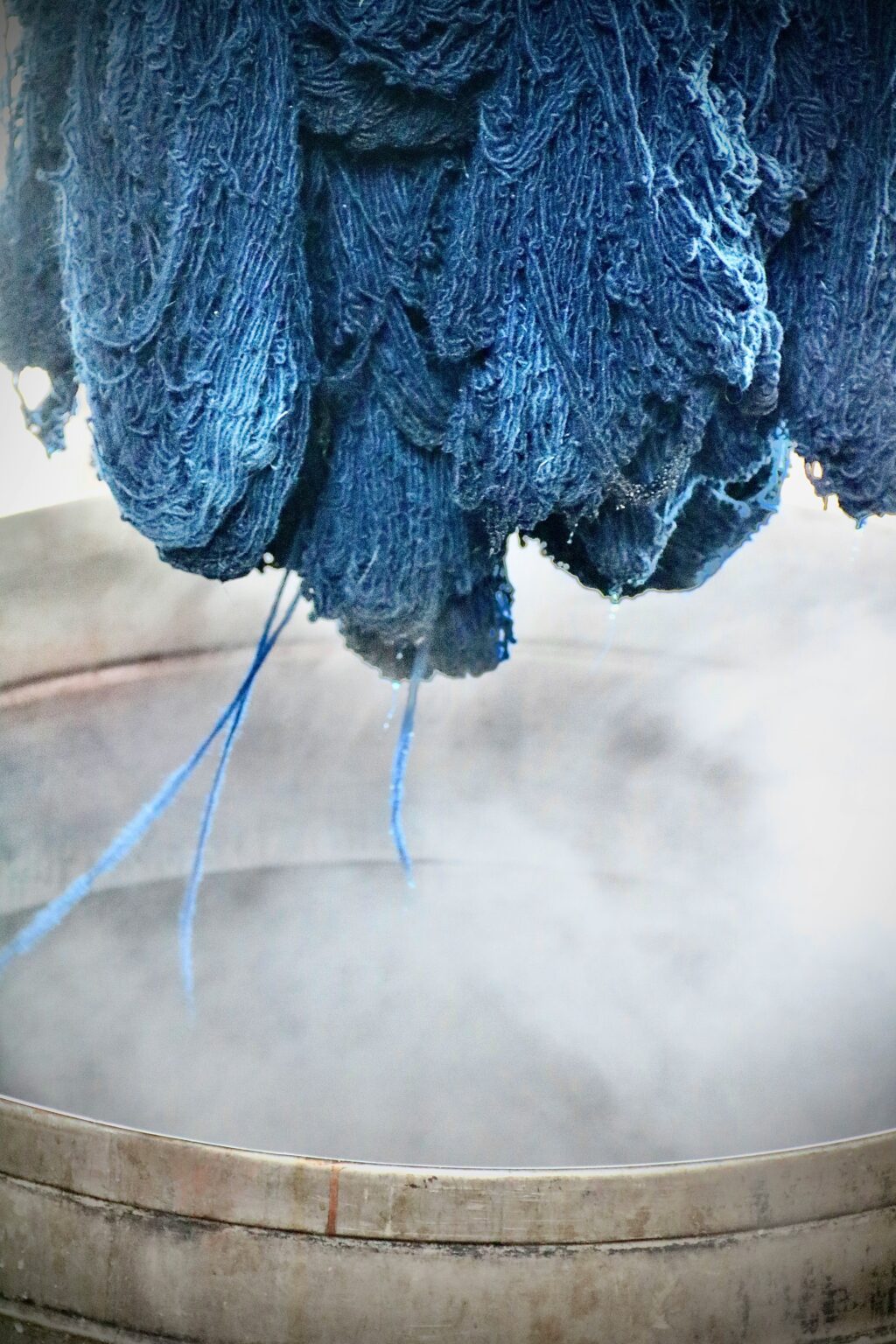 Blue yarn being dyed in a steaming vat during the textile dyeing process, where magnesium acetate is used as a mordant for better dye fixation.