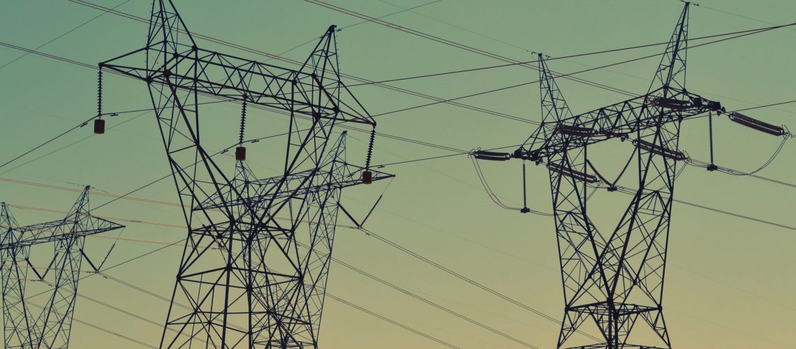 Electric power lines and transmission towers silhouetted against a dusk sky.