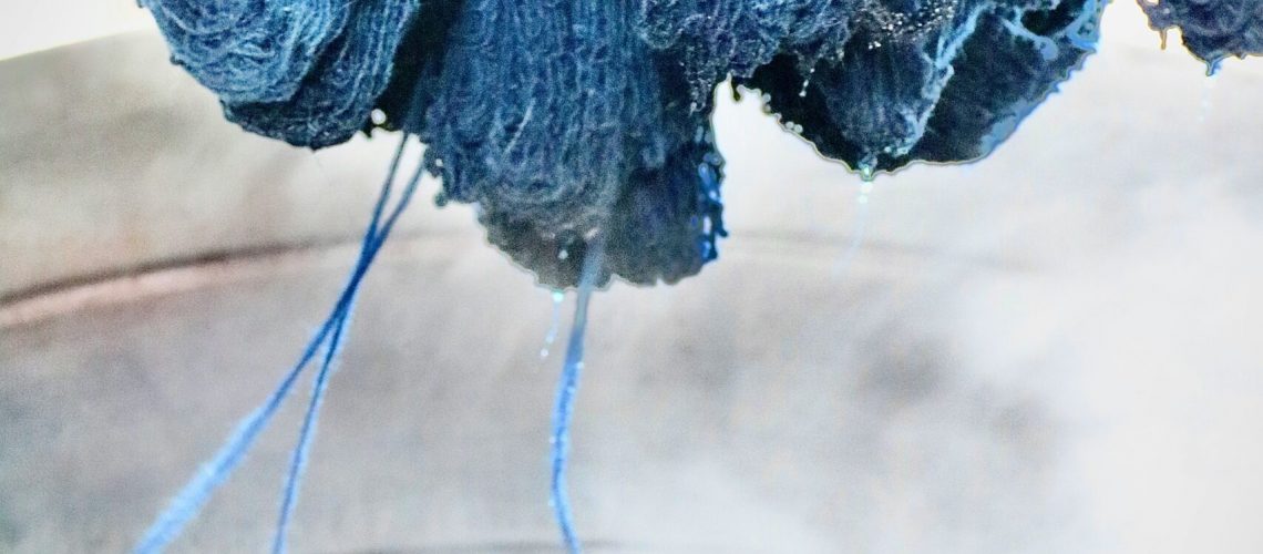 Blue yarn being dyed in a steaming vat during the textile dyeing process, where magnesium acetate is used as a mordant for better dye fixation.