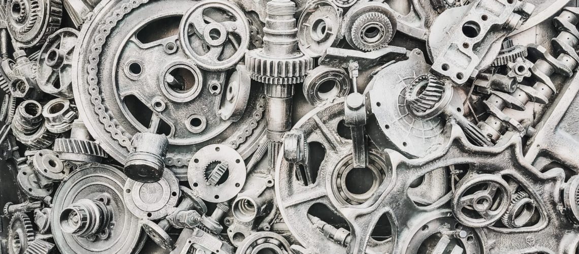 Close-up of various mechanical gears and metal components, representing the industrial applications of Hafnium compounds