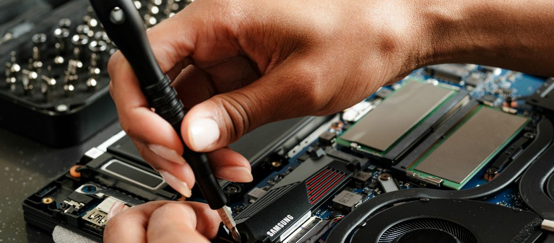 Close-up of hands assembling a semiconductor component with a screwdriver, using zirconium (IV) chloride in the process for creating thin film layers and enhancing material stability.